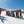 skiklasje met kinderen op een rij en twee leraren in besneeuwd skigebied die hun skistok in de lucht houden