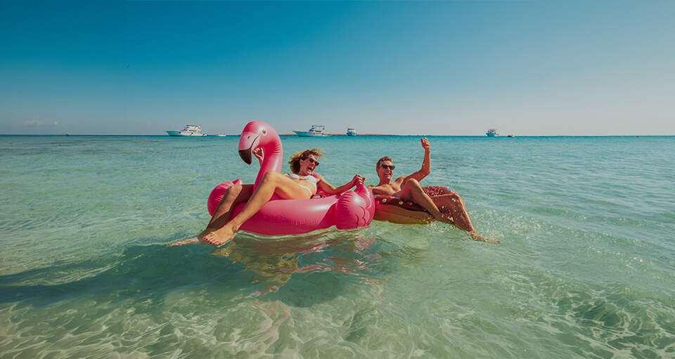 man vrouw in zee met opblaasflamingo