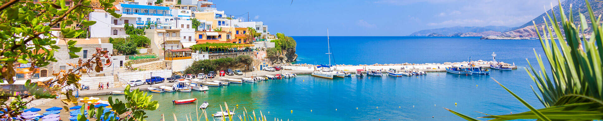 kleine haven met bootjes en gekleurde huisjes in aquablauwe zee omgeven door groen tijdens een vakantie in september