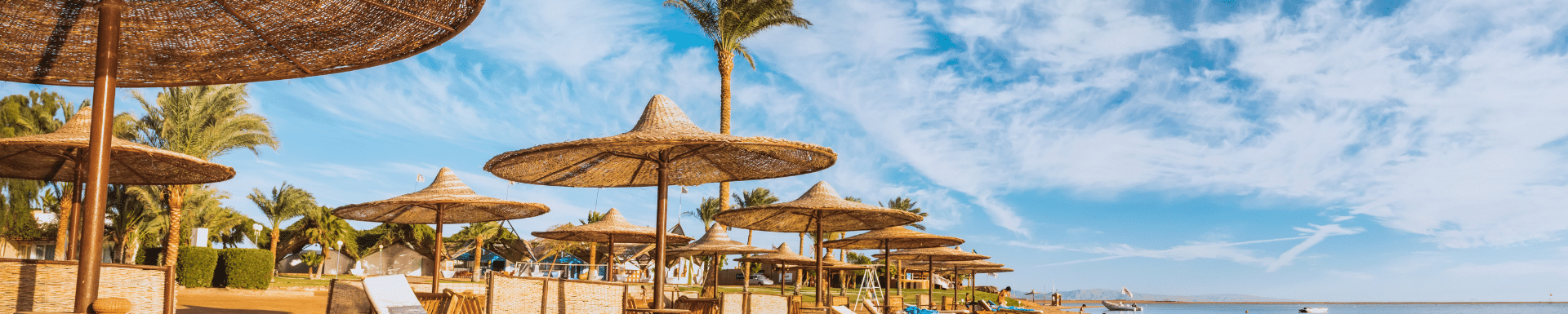 rieten parasols en ligbedjes op strand aan de rode zee, egypte