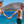 man en vrouw in badkleding lopen lachend hand in hand langs aquablauwe zee met rotsen en stijger op de achtergrond