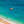 Strand met rieten en gekleurde parasollen en mensen die zwemmen in aquablauwe zee in Spanje