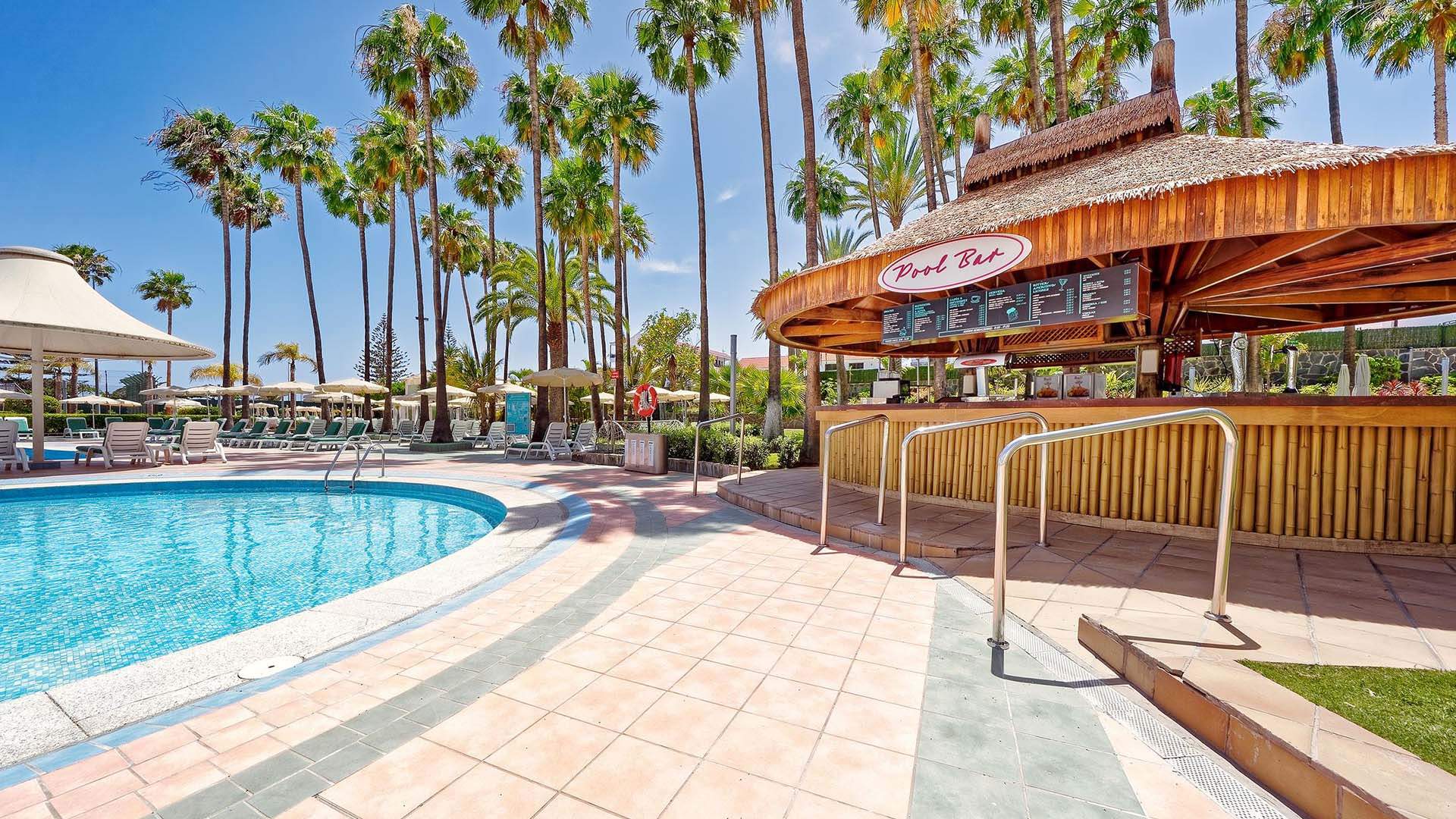 Bull hotel met zwembad en houten overdekte bar omgeven door palmbomen