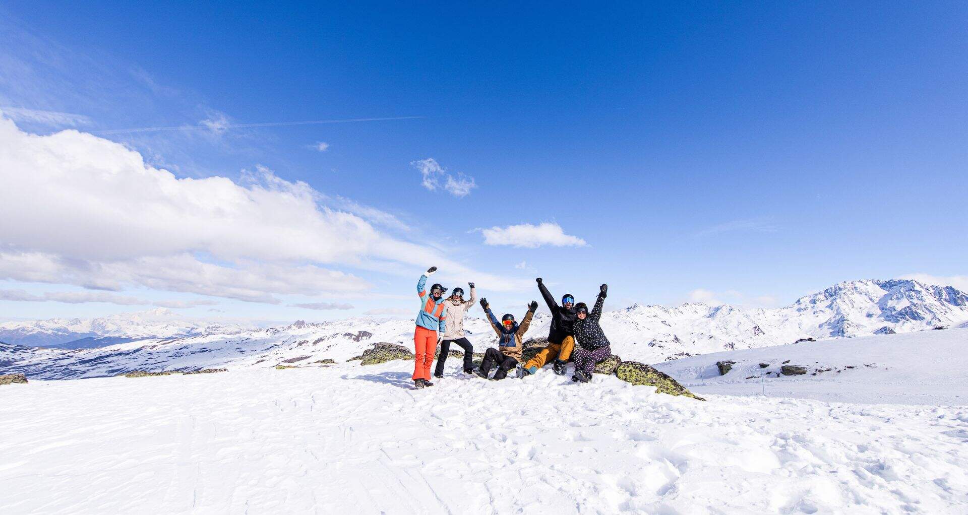 groep vrienden op een skipiste met hun armen in de lucht