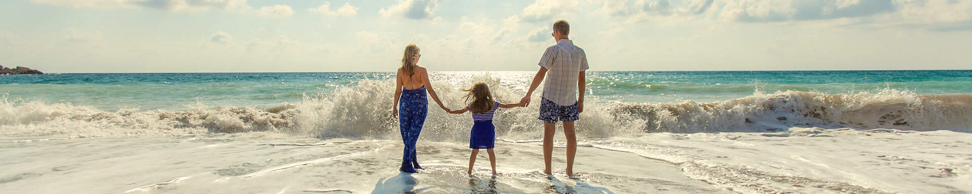 Ouders en kind hand in hand kijkend naar de zee 