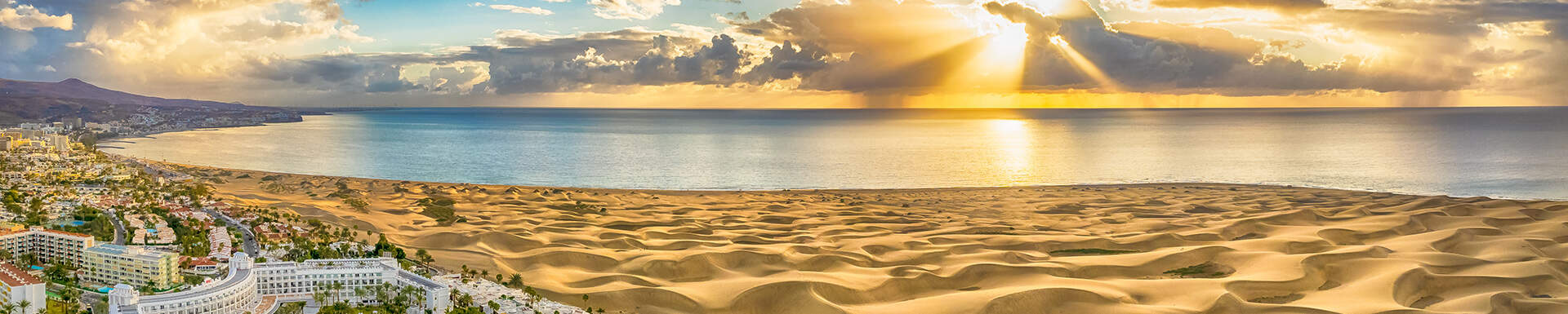 Uitzicht over de zee, duinen en hotels van Maspalomas, Gran Canaria tijdens ondergaande zon