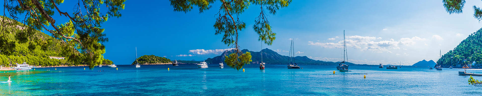 Helderblauw water met bootjes in een baai in Mallorca, Spanje