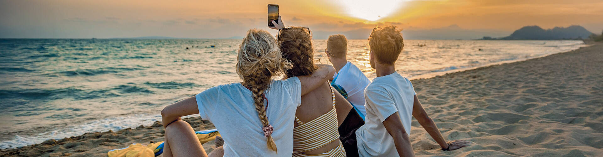 jongeren op strand maken foto van ondergaande zon