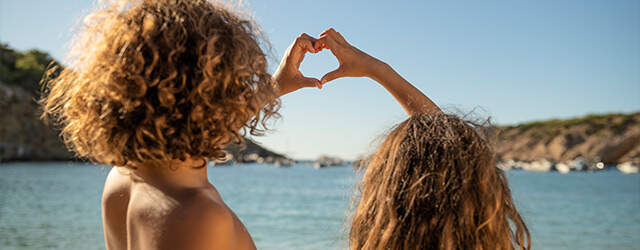kinderen maken een hart met handen met uitzicht over zee