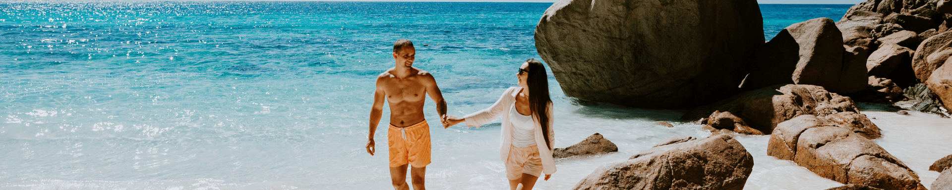 Koppel houdt handen vast en loop langs het kristalheldere water