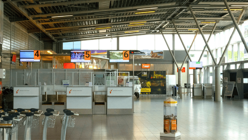 Binnenzicht van Groningen Eelde Airport met incheckbalies baggagetrolleys