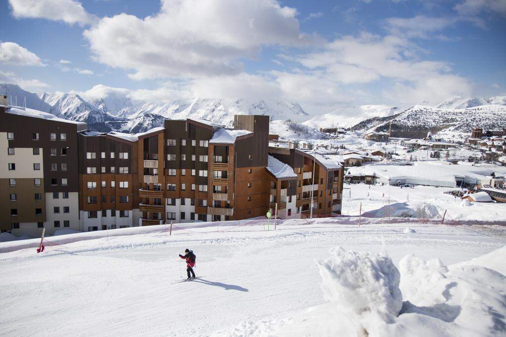 snowboarder op piste voor residence les berges alpes d'huez