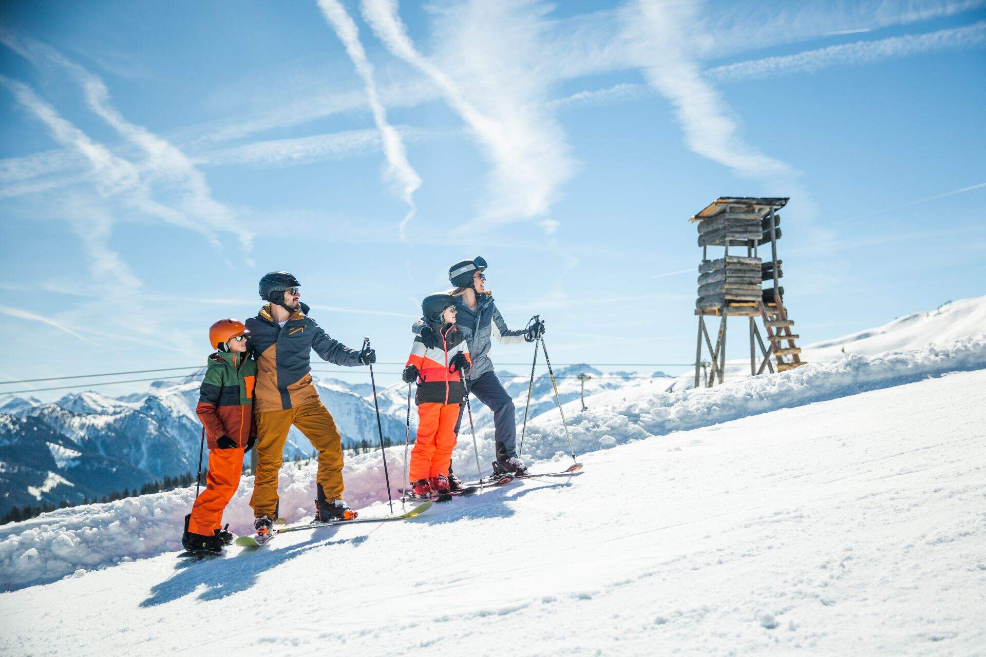familie met vader moeder zoon en dochter in skikleding op besneewde berg kijken de berg op