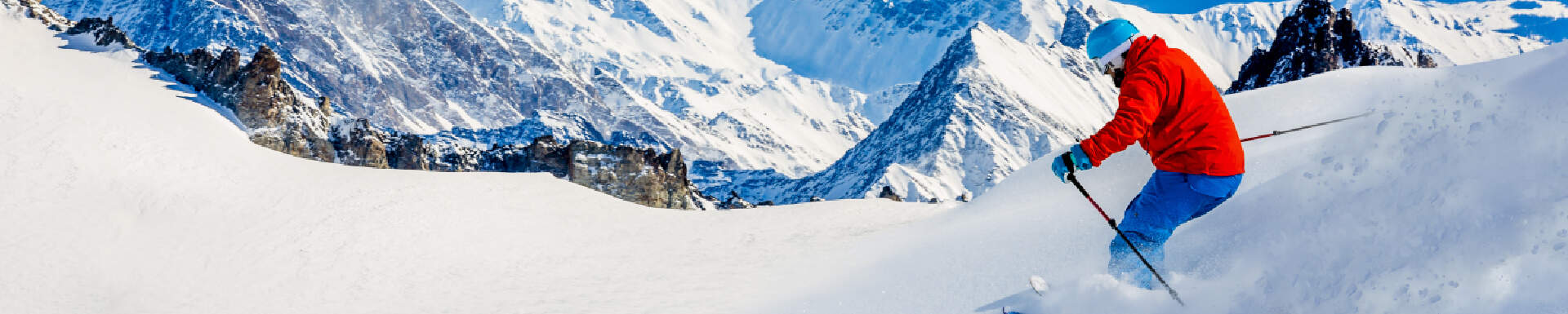 Persoon in oranje-rood pak skiet van een piste