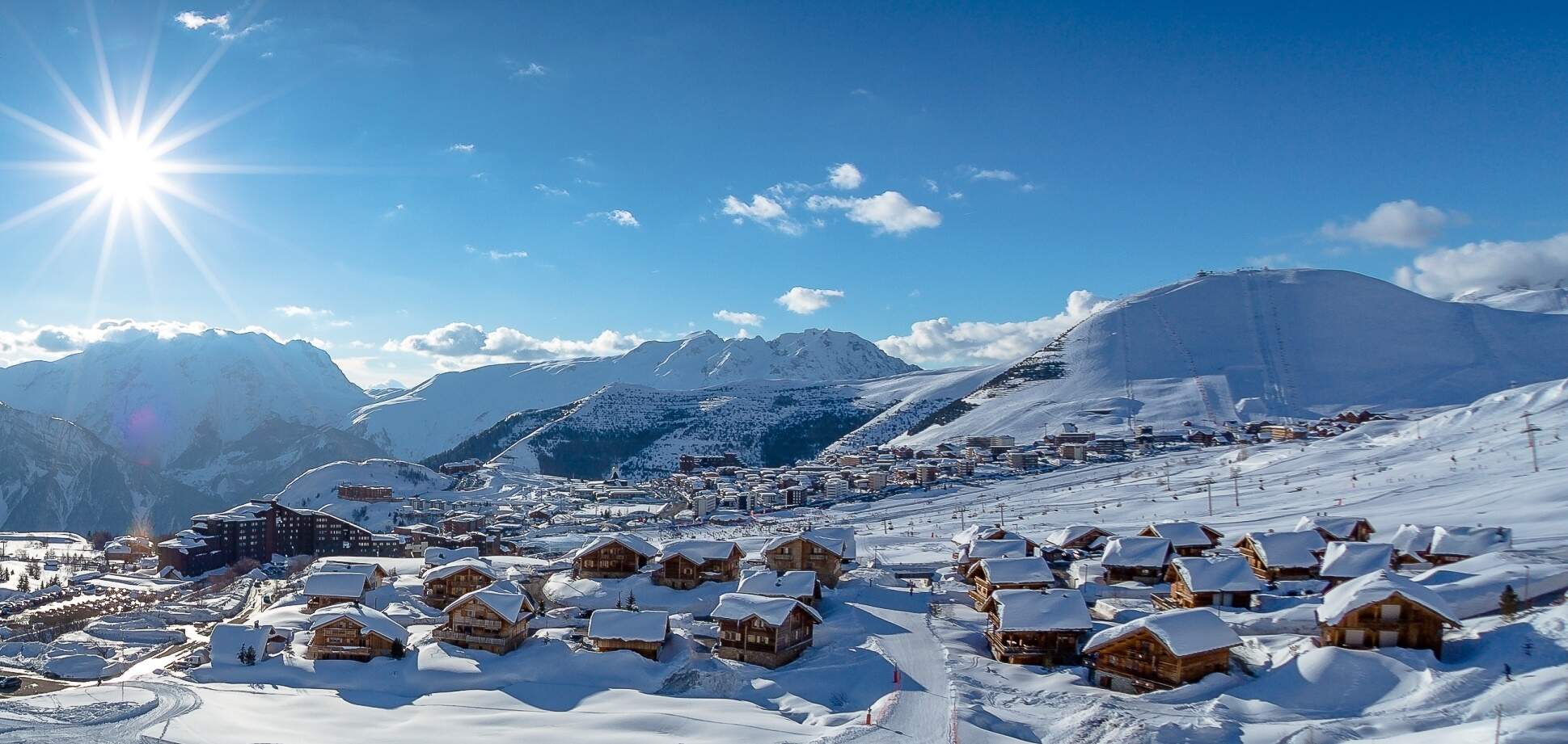zonnig skigebied met besneeuwde chalets en bergen