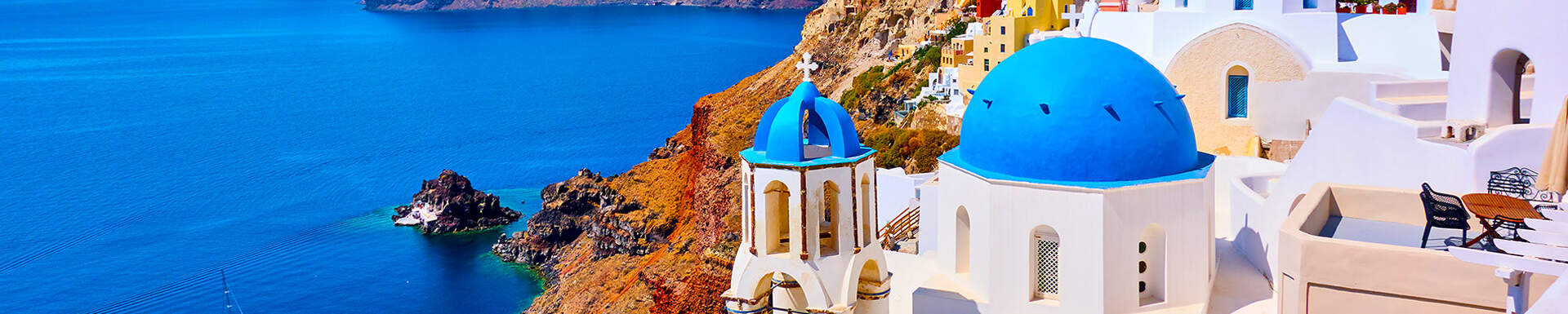 Typisch Griekse witte huizen met blauwe koepels aan rotsachtige kust met blauw zee in Oia, Santorini
